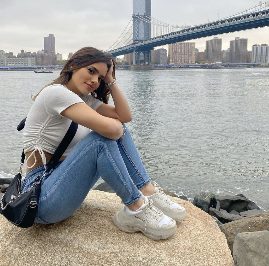 Portrait by the river with a city bridge in the background